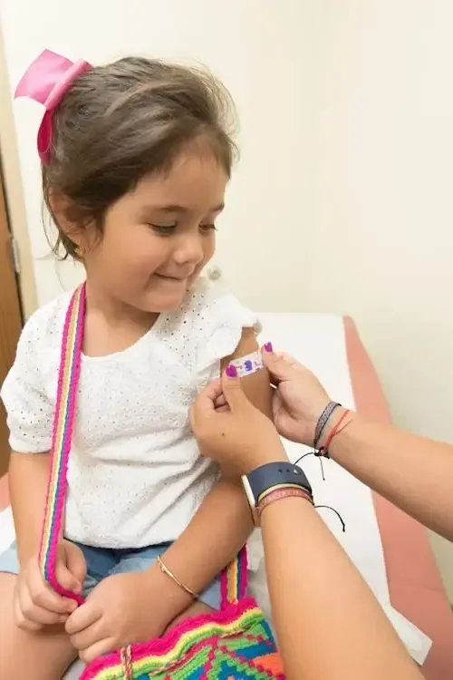 a doctor putting a bandaid on a girl after a shot